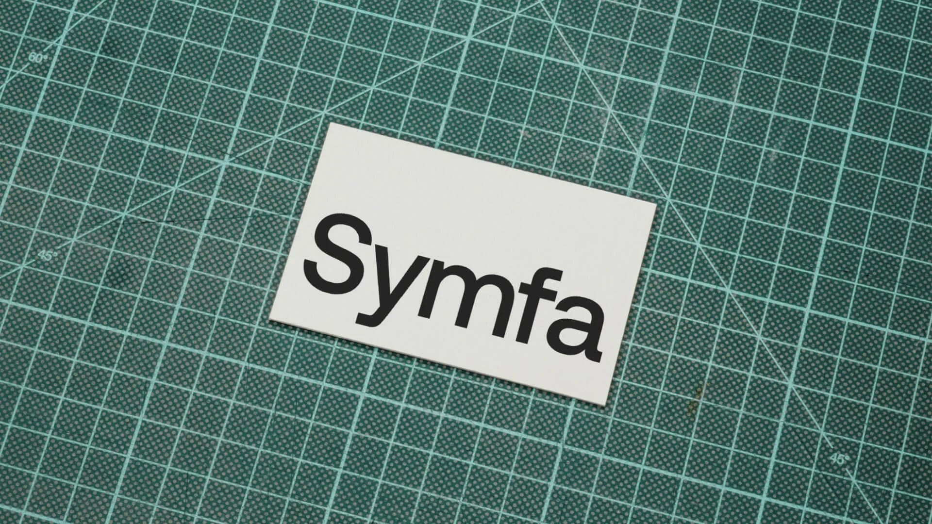 Symfa logo printed on white card placed on green cutting mat background